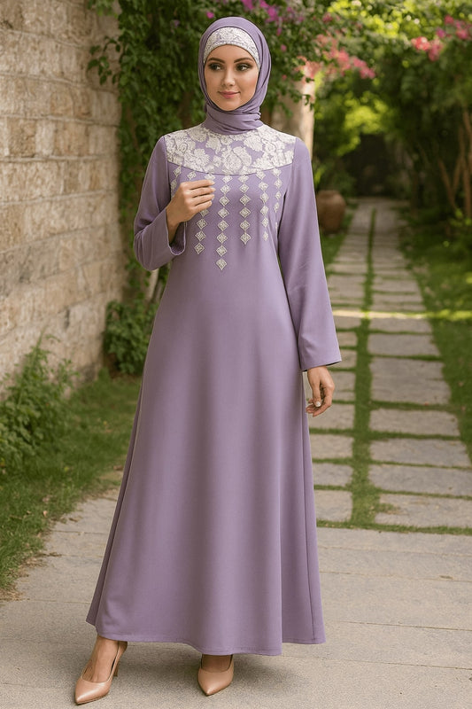 Woman in a long, light purple dress with white lace details standing outdoors on a stone path.