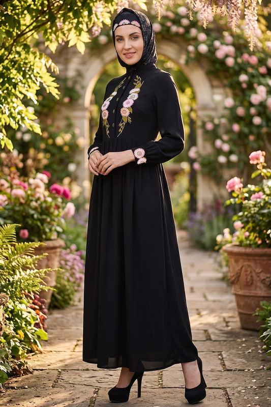 Woman in a black dress with floral details standing in a garden with flowers and arches.