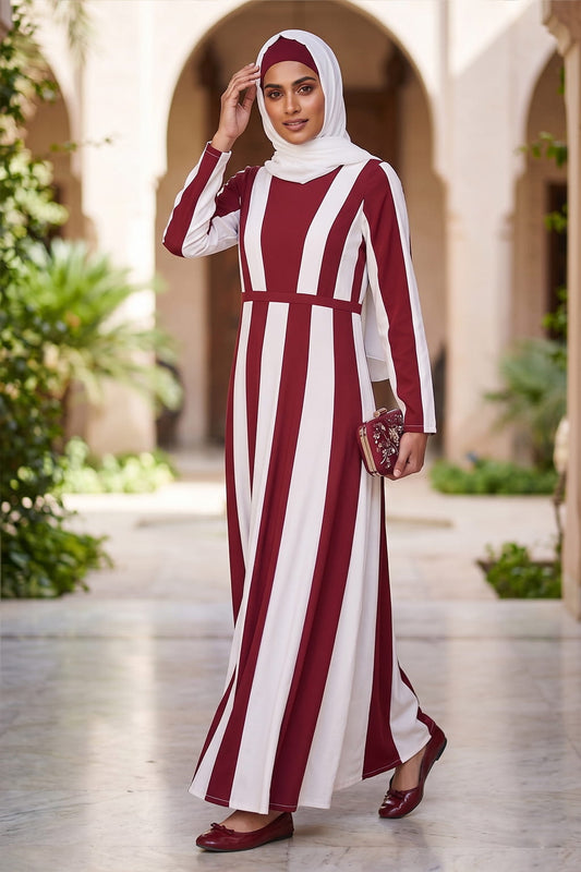 Woman wearing a red and white striped dress in an outdoor setting with arches and greenery.