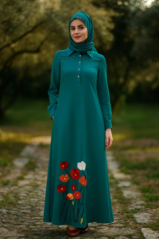 Woman wearing a teal dress with floral embroidery standing outdoors.