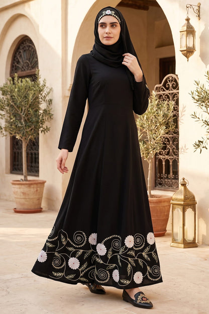 Woman wearing a black abaya with white embroidery in an outdoor setting.