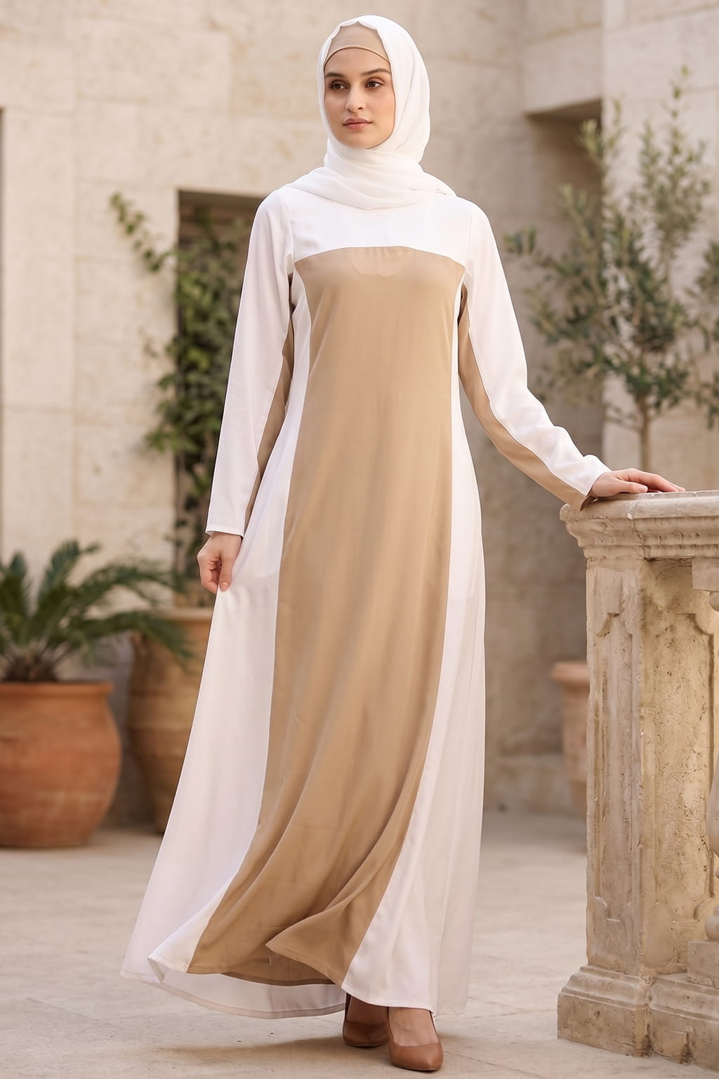 Woman wearing a long, two-tone dress with a white top and brown bottom, standing outdoors.