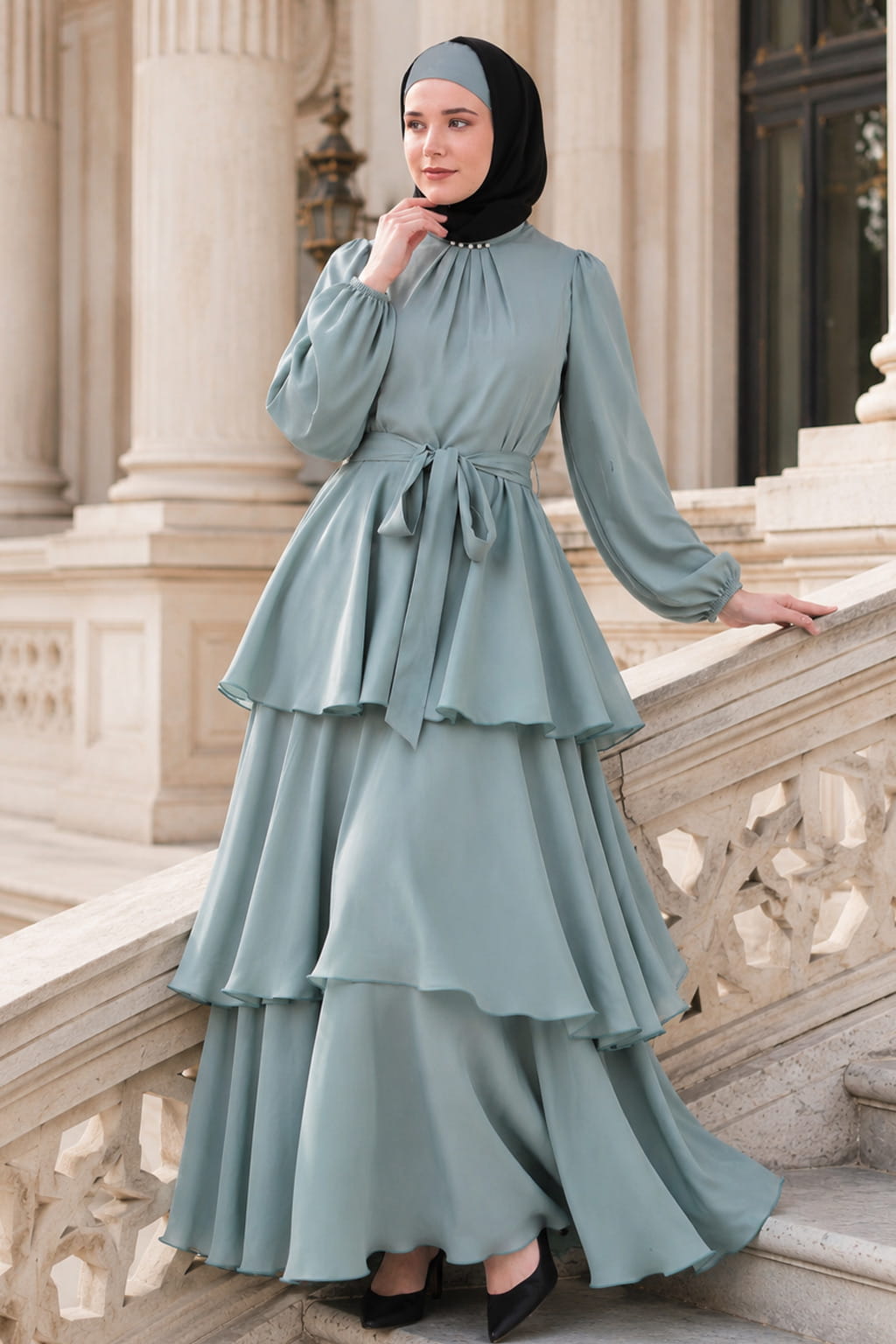 Woman wearing a light blue dress with ruffled layers in front of classical architecture.