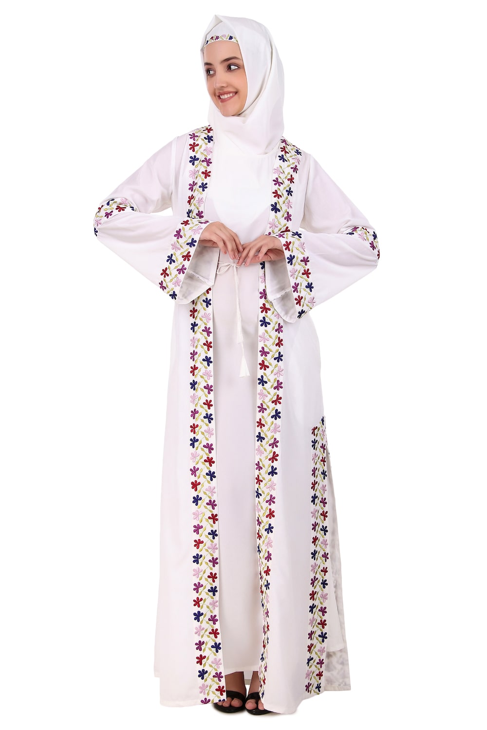 A woman wearing a white abaya with heavy embroidery and a detachable sleeveless inner layer, featuring front open design with drawstrings and bell sleeves.