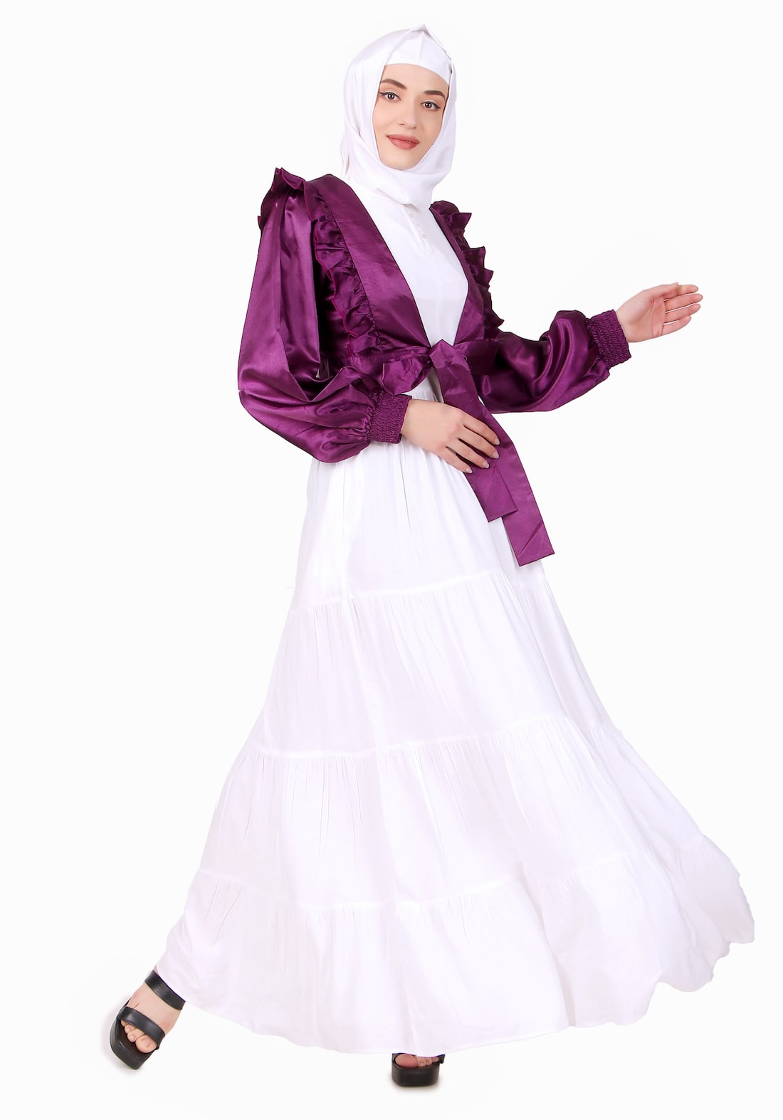 A woman wearing a white and purple multi vertical layer abaya with a round neck and a purple satin jacket with straight sleeves and fabric strap closure.