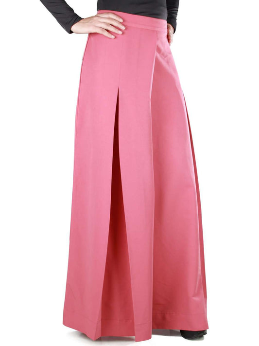 A person standing and modeling dusty pink palazzo pants with inverted pleats and utility polckets on the sides.