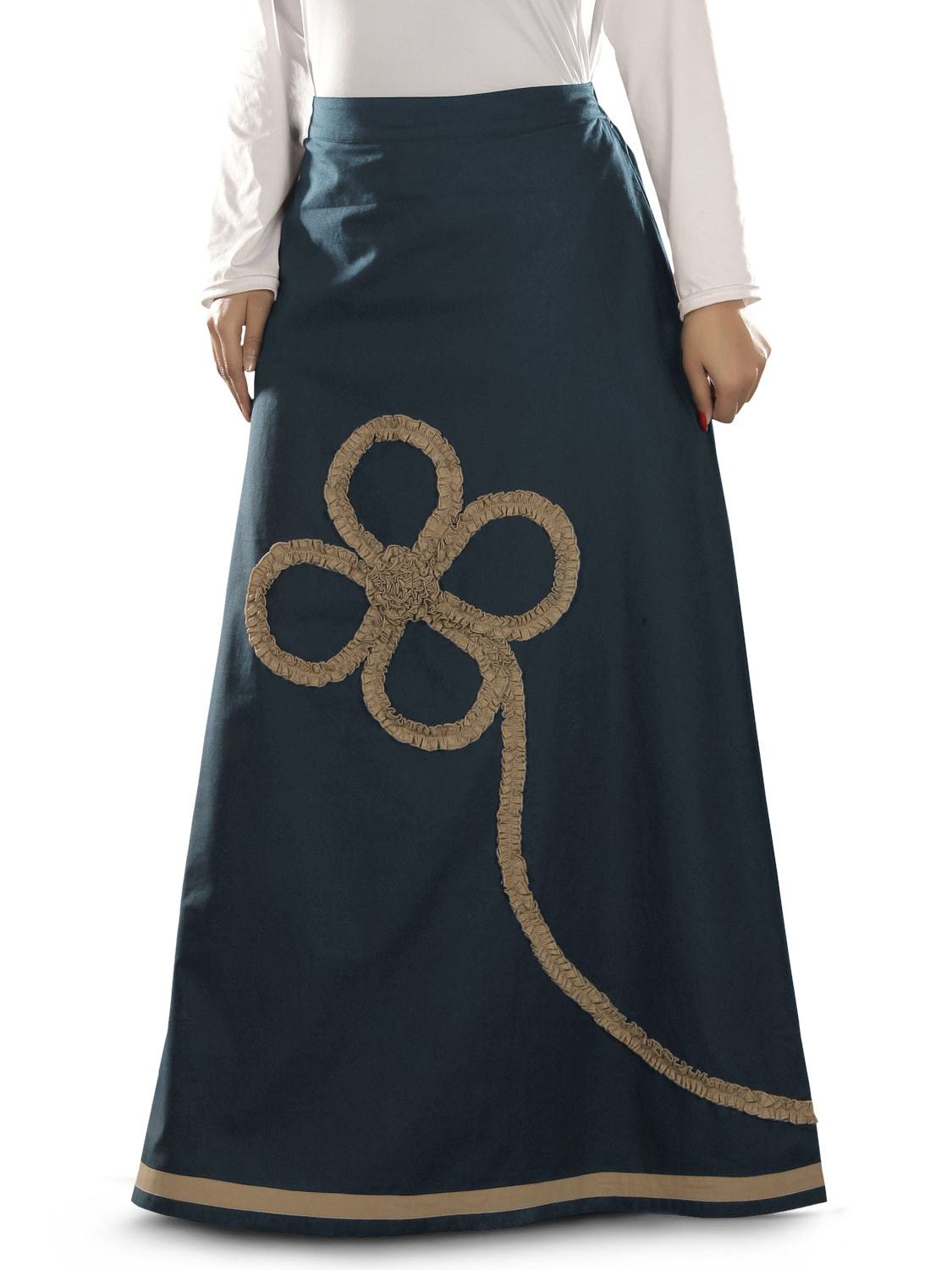 A navy blue A-line skirt with a large frilled floral motif in a contrasting color embroidered on the lower side, with elastic waist on the back and a utility pocket on the left side.