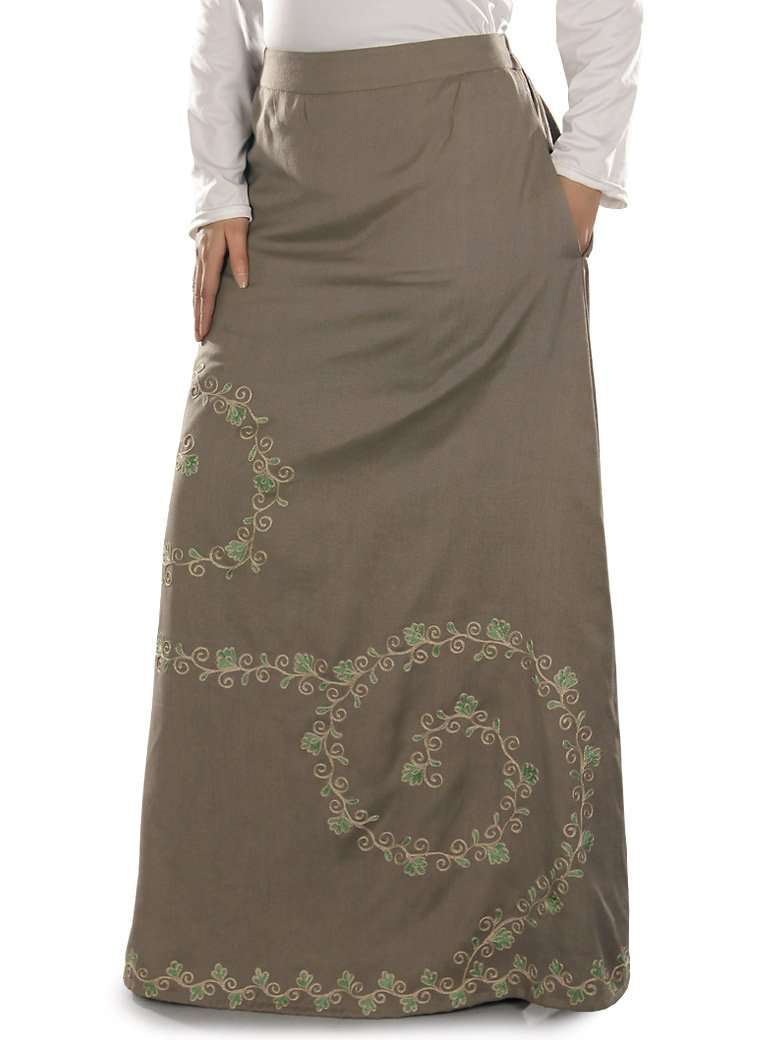 A khaki-colored A-line skirt with beautiful machine hand embroidery around the lower border, featuring utility pockets on the sides and an elastic waist on the back.
