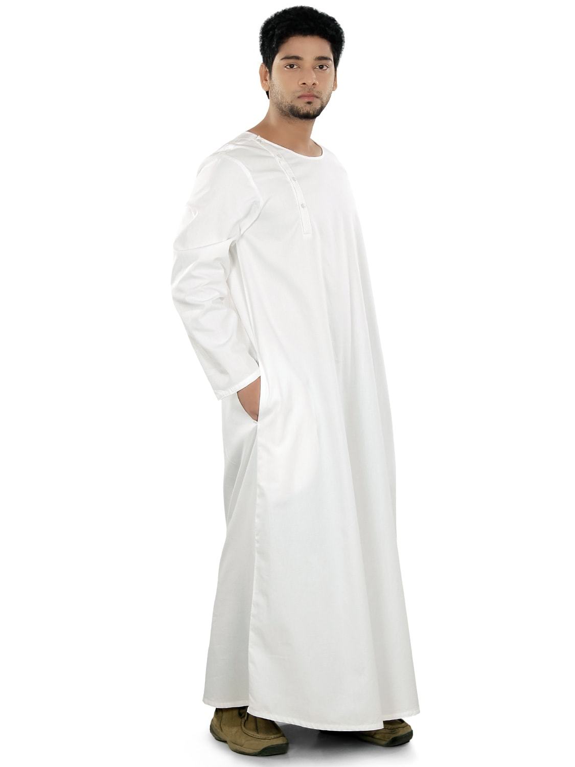 A man wearing a white galabiyya with a round neck, side open placket with buttons, and utility pockets on both sides.