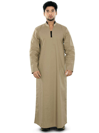 A man wearing a beige ghaniya with a band collar, front open placket, and utility pockets on the sides. The garment appears to be made of a cotton-like fabric.