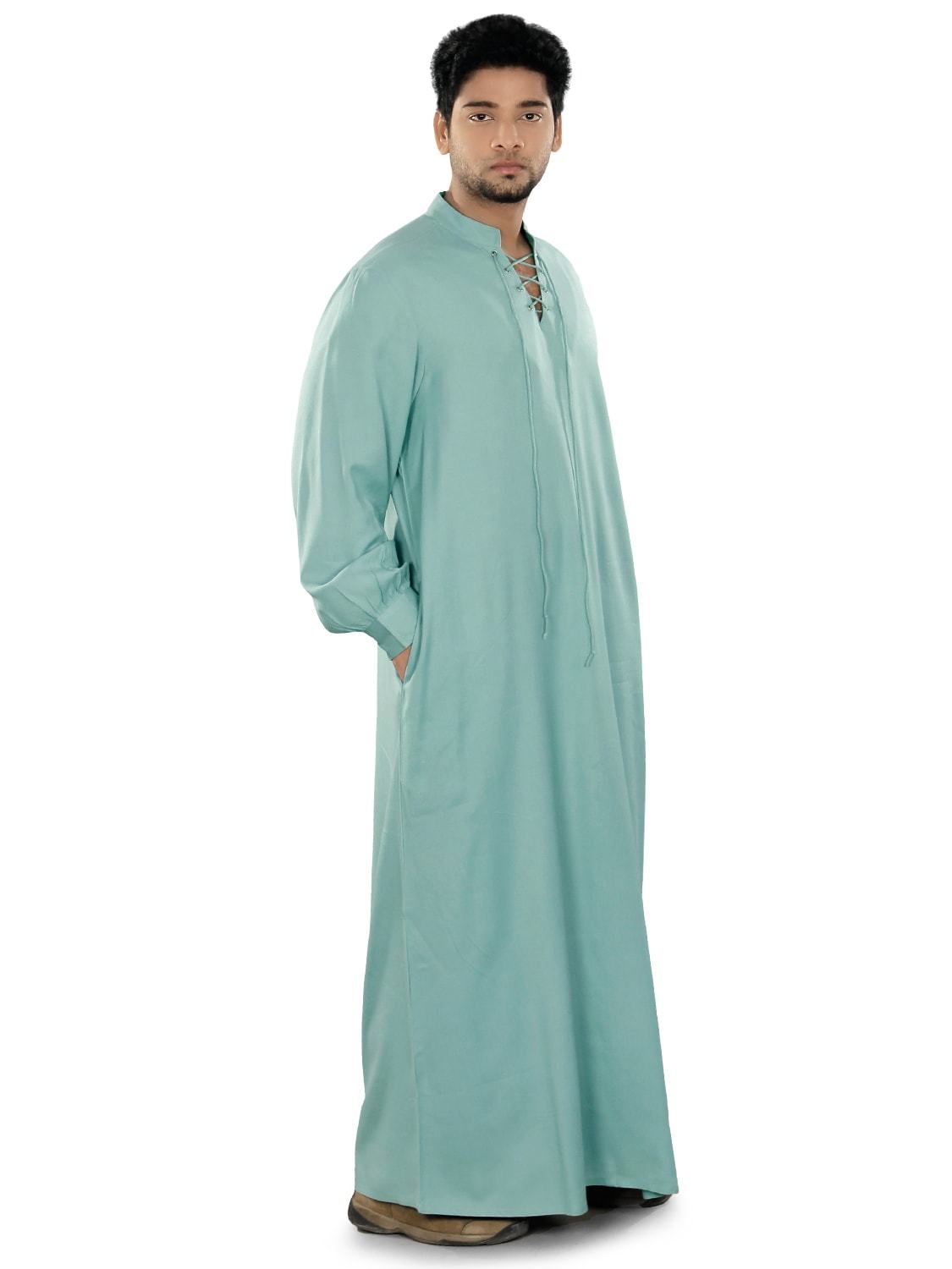A person wearing a light blue galabiyya with a V-neck collar and front pockets. The fabric appears soft and is likely to be lightweight.