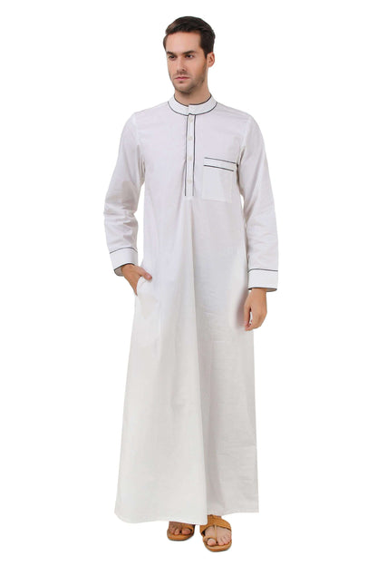 A man wearing a white cotton galabiyya with a band collar neckline, black piping finishing on the collar and chest pocket, and utility pockets on the sides.
