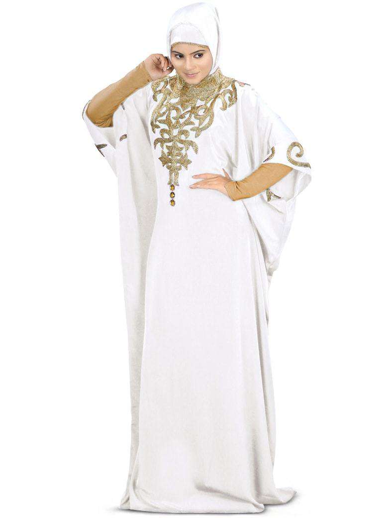 A woman wearing a white hand embroidered Kaftan with a band collar neckline and adjustable belt at waistline.