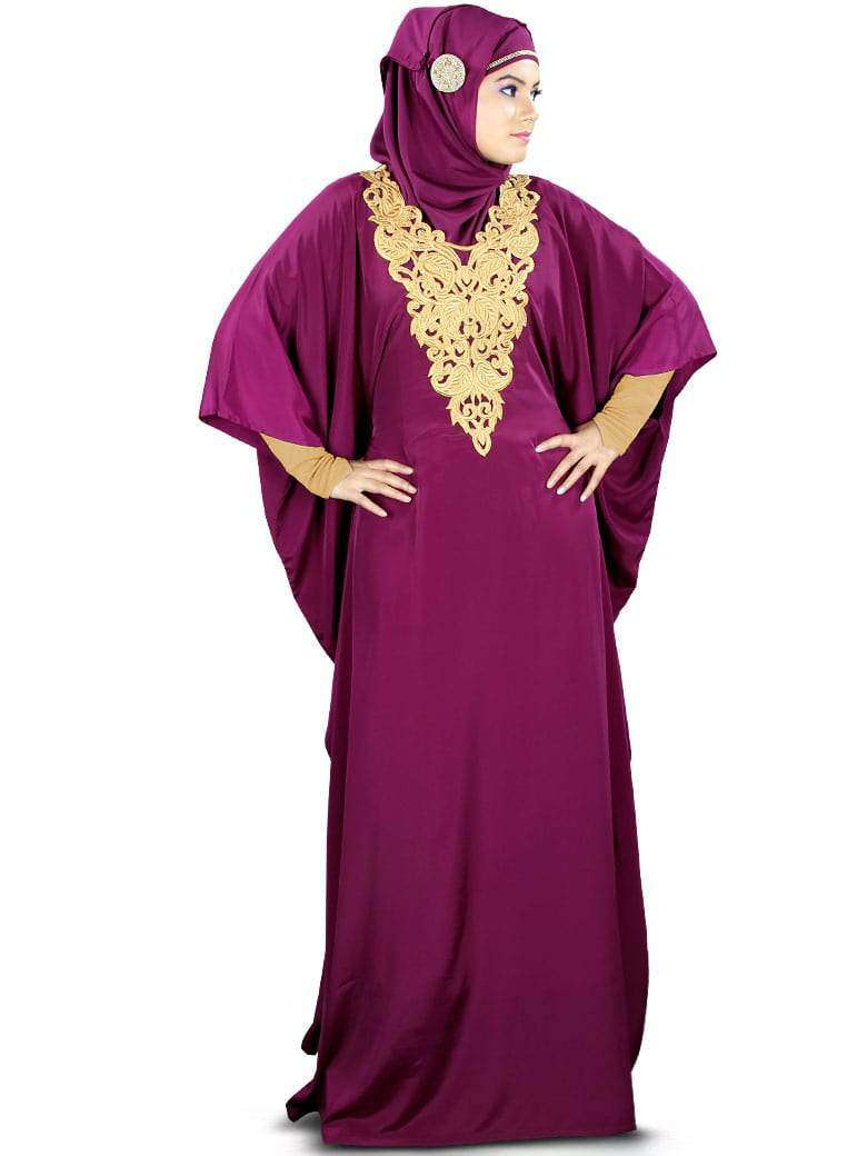 A woman wearing a wine purple Kaftan with gold embroidery at the neckline and a square or rectangular hijab. The Kaftan has a cutwork neckline and gold floral embroidery on the neck.