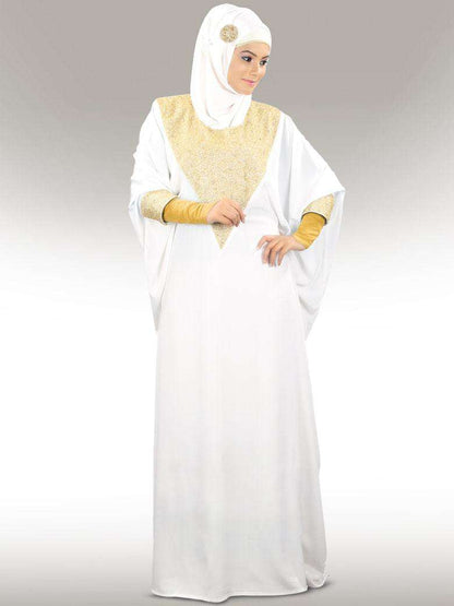 A woman wearing a white kaftan with golden bead hand embroidery around the neckline and cuffs, standing against a plain background.