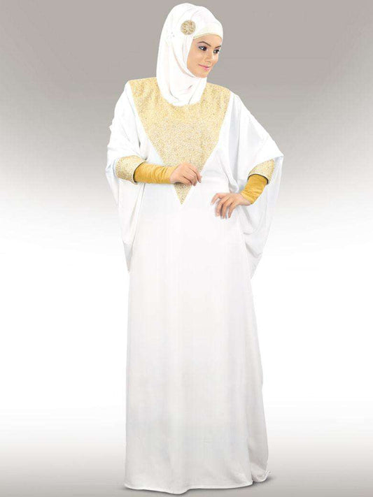 A woman wearing a white kaftan with golden bead hand embroidery around the neckline and cuffs, standing against a plain background.