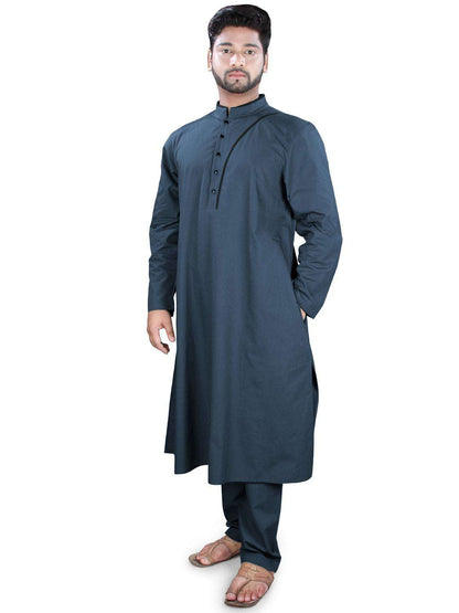 A man wearing a navy-blue kurta pajama set with a band collar neckline, front open placket with black contrast strip, and side openings. The pants have a drawstring waist and the outfit is completed with straight sleeves and utility pockets.